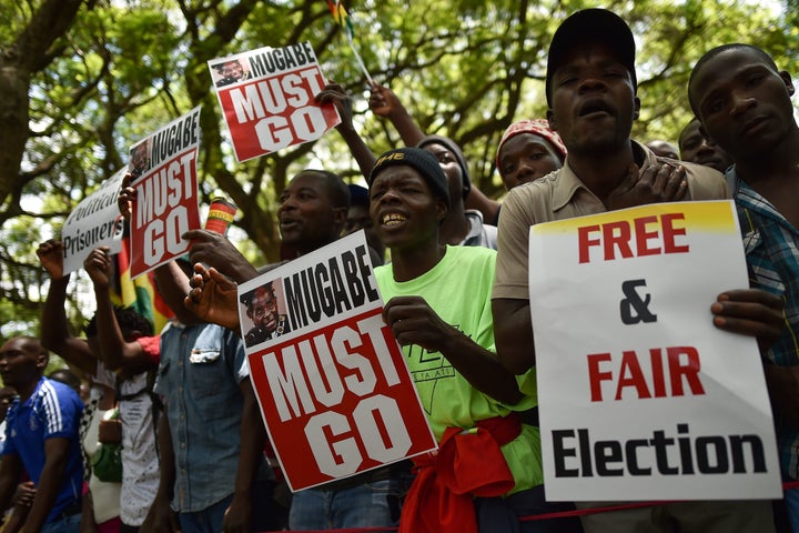 Protesters hold signs during a gathering in Zimbabwe's capital of Harare on Nov. 21, 2017, calling for Mugabe to step down.