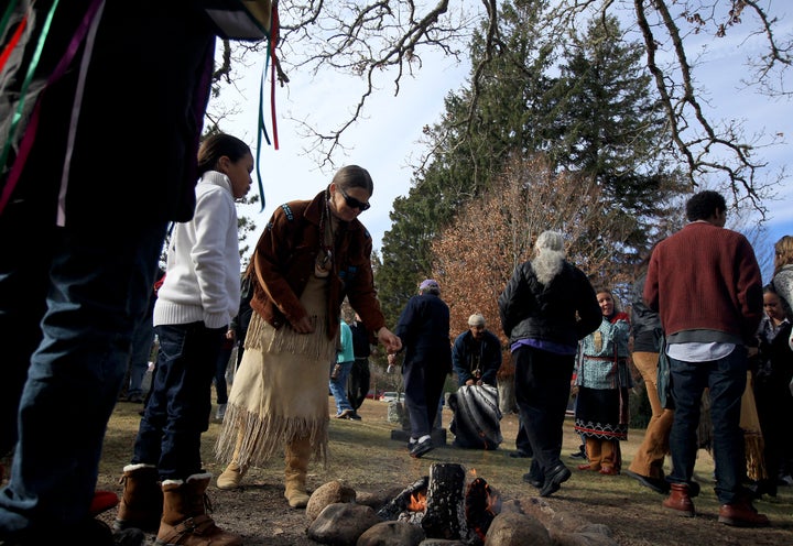 Mashpee Wampanoag tribe members sprinkle tobacco over a fire during a Native American Thanksgiving celebration on Nov. 23, 2013, at the Old Indian Meeting House in Mashpee.