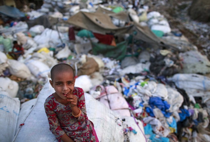 A girl sits on a sack of discarded clothes at a slum in Mumbai, India, on April 20, 2016.