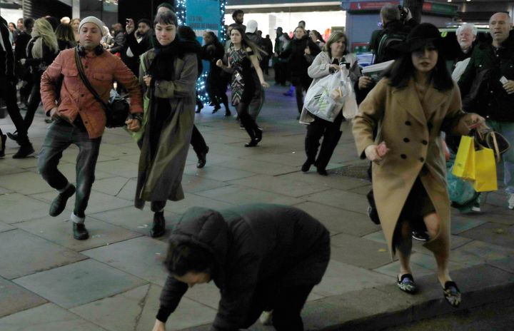 A woman stumbles as people run down Oxford Street on Friday night.