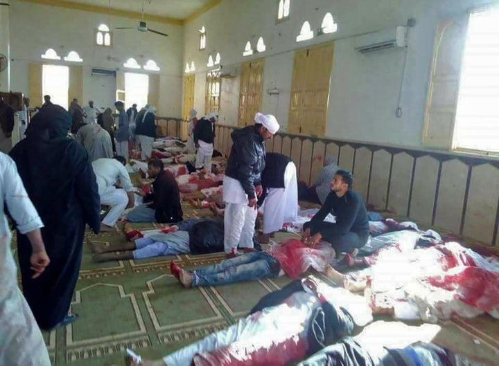 Egyptians walk past bodies following a gun and bombing attack at the Rawda mosque, roughly 40 kilometers west of the North Si