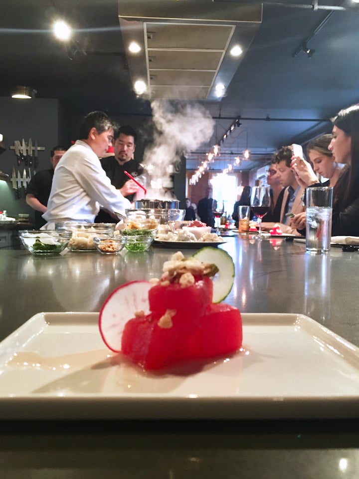 In the foreground: watermelon poke; in the background: Chef Yamaguchi prepares meals for guests