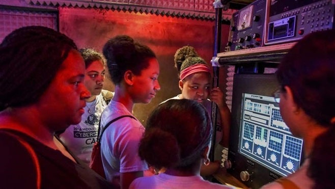 Participants in GenCyber, a cybersecurity summer camp for middle-school girls, work to solve a mystery at the Spy Museum in Washington, D.C. State officials are trying to get more students, veterans and women interested in cybersecurity careers.