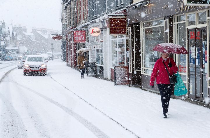 The Met Office has issued ice warnings as temperatures are set to plummet; a pedestrian is pictured walking across snowy pavements in Scotland, above