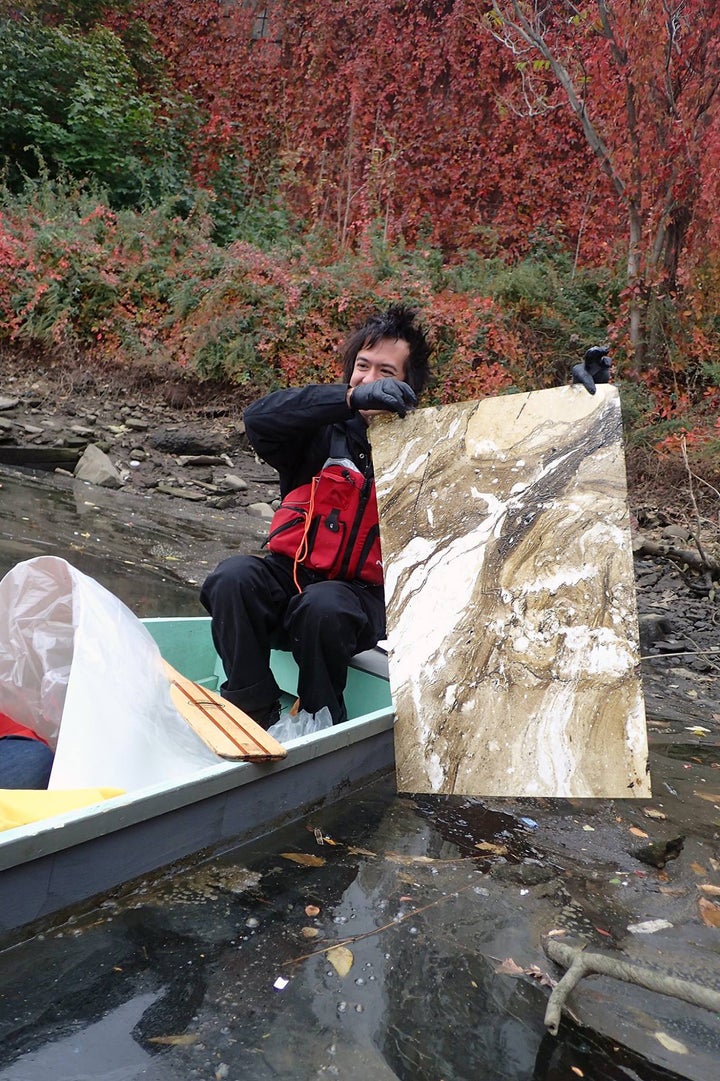 Sto pulling a pollution suminagashi print from a polluted waterway.