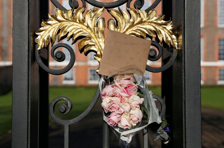 Flowers and a card addressed the Britain's Prince Harry and Meghan Markle are seen attached to the railings of Kensington Palace in London on Nov.28, 2017.