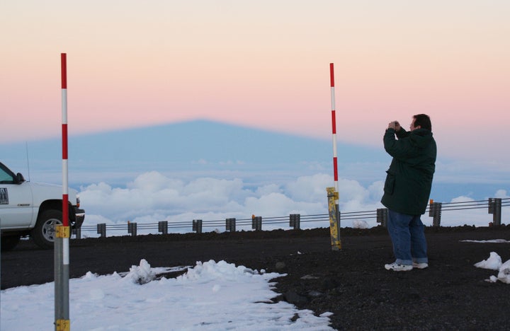 A visitor takes photos of snow on Mauna Kea in this undated photo. The red-and-white poles measure snow depth.