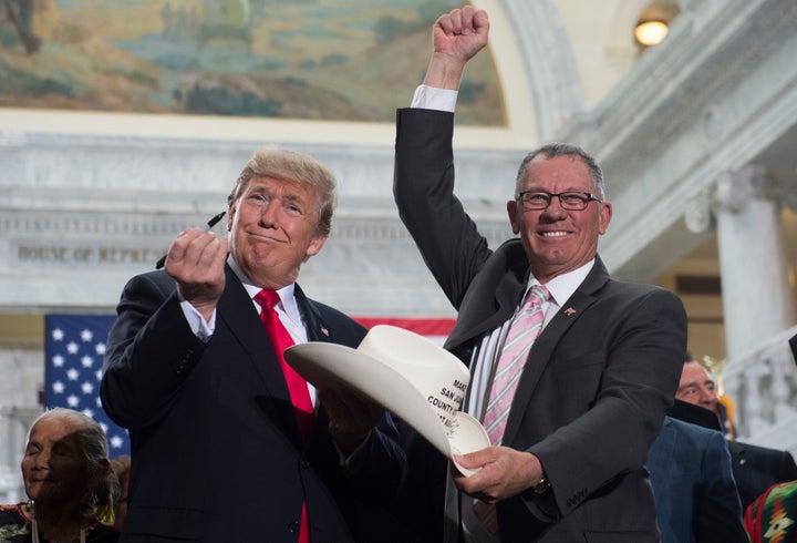 President Donald Trump holds up a pen after signing the hat of Bruce Adams, chairman of the San Juan County Commission and a vocal opponent of Bears Ears National Monument. 