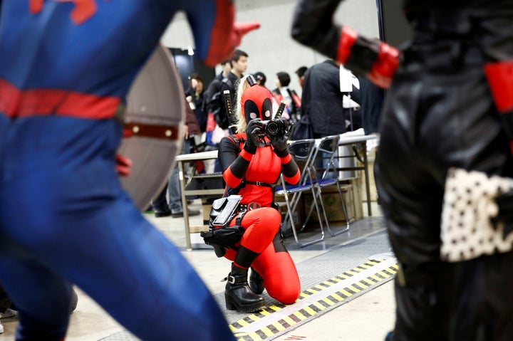 A woman in a Deadpool costume taking the picture of other cos players at Tokyo Comic-Con, Dec. 1.