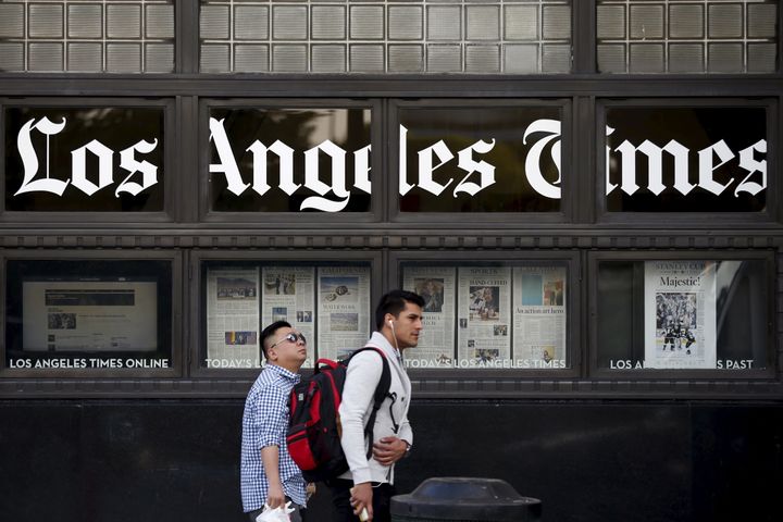 People walk past the LA Times building in Los Angeles.