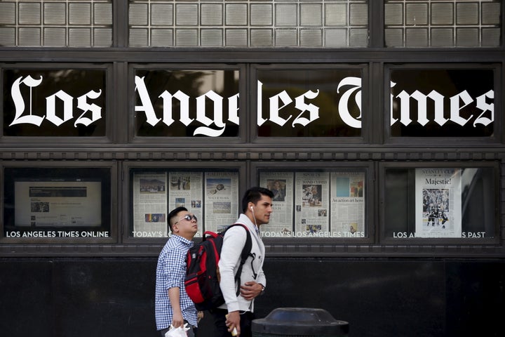 People walk past the LA Times building in Los Angeles.