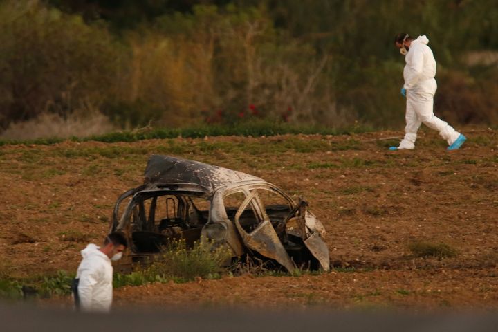 Police and forensic experts inspect the wreckage of a car bomb that killed Caruana Galizia