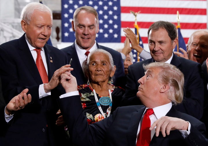 President Donald Trump hands a pen used to sign an executive order to Sen. Orrin Hatch (R-Utah) after announcing on Monday big cuts to a pair of Utah national monuments, as Interior Secretary Ryan Zinke and Rep. Mike Lee (R-Utah) applaud at the Utah State Capitol in Salt Lake City, Utah.