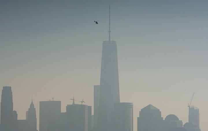 A helicopter flies over the Hudson River on a hazy day in New York City.