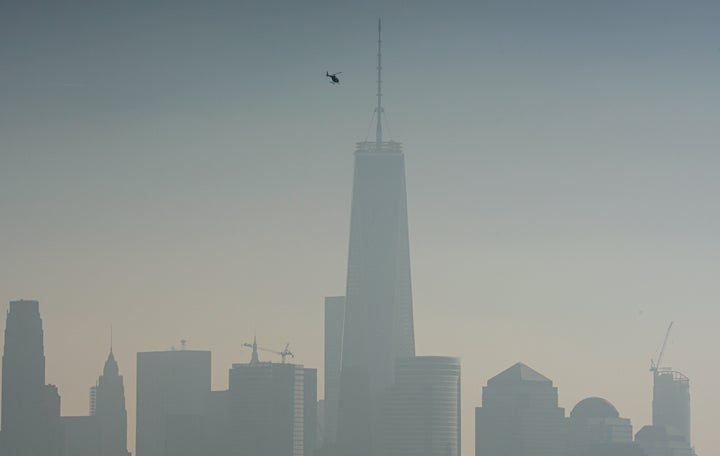 A helicopter flies over the Hudson River on a hazy day in New York City.