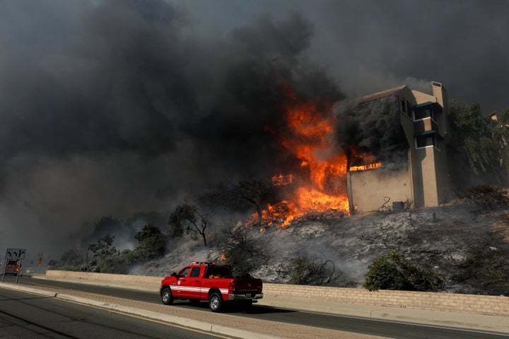 A fire officials drives past a burning home in Ventura, California, on Tuesday.