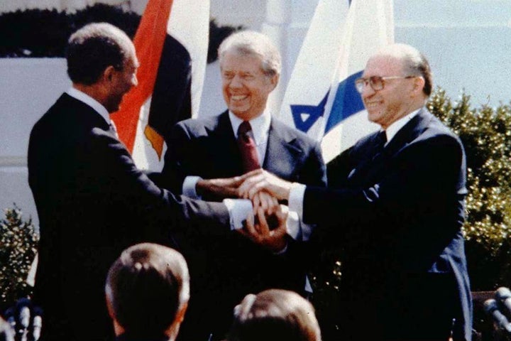 President Jimmy Carter celebrates with Egyptian President Anwar Sadat and Israeli Prime Minister Menachem Begin at the signin