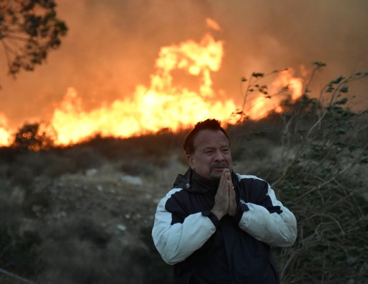 A man prays as the Creek fire advances behind him in the San Fernando Valley area of Los Angeles.