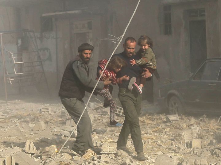 Nearly one in four civilians killed in Syria is a child, a report has found; Syrian men are seen carrying their children to safety following residential air strikes in Damascus, Syria, on December 3