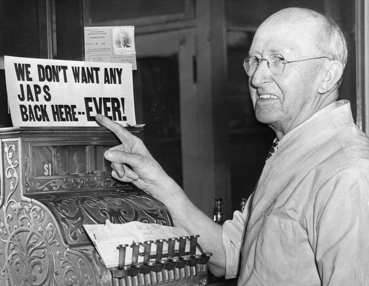 A barber points to his own anti-Japanese sign after Japanese-Americans were incarcerated during World War II.