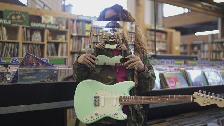 H.E.R. playing her Fender Surf Green Duo Sonic Offset as part of a new collaboration with the guitar company 