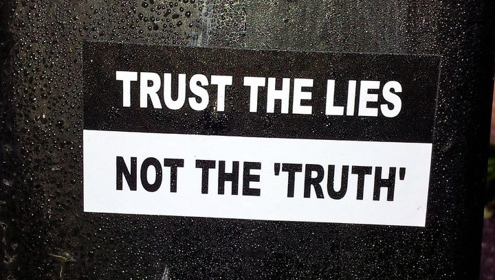 photo saying “trust the lies, not the ‘truth’” (Thomas Guest/Flickr) 