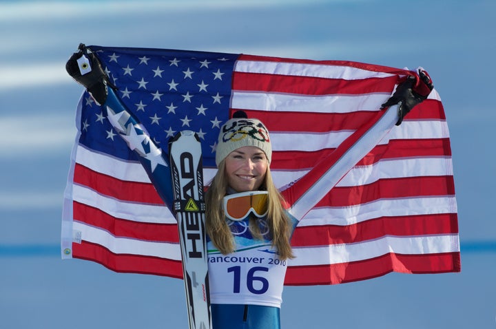 Lindsey Vonn holds up the flag after winning gold in the women's downhill competition at the 2010 Winter Olympics, Feb. 17, 2010.