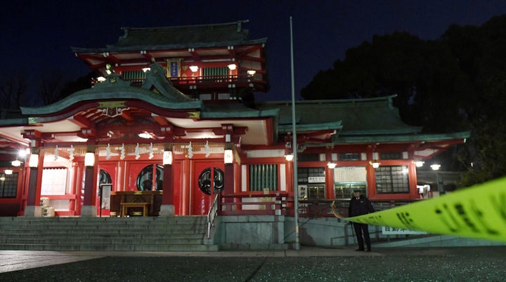  A policeman stands guard in front of the main temple of the Tomioka Hachimangu shrine in Tokyo, Japan in this photo tak