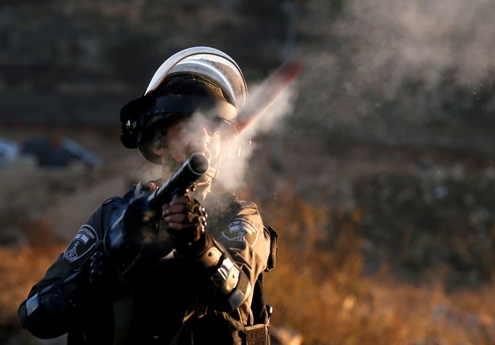 An Israeli soldier fires tear gas towards Palestinian protestors. 