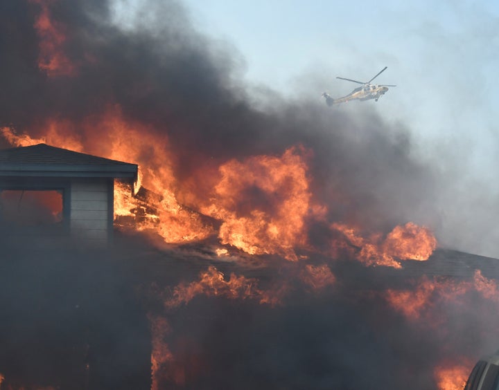 A firefighting helicopter tries to make a water drop in heavy winds after an early-morning fire broke out in the Kagel Canyon area in the San Fernando Valley north of Los Angeles, on Dec. 5, 2017.