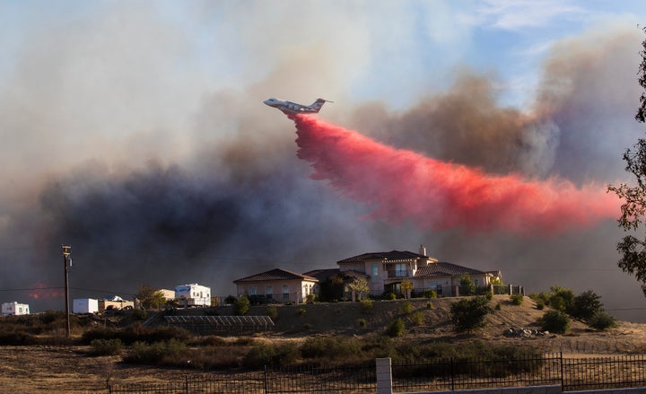 A plane drops fire retardant to stop the wind-driven Liberty fire near Los Alamos Road on Dec. 7, 2017, in Murrieta.