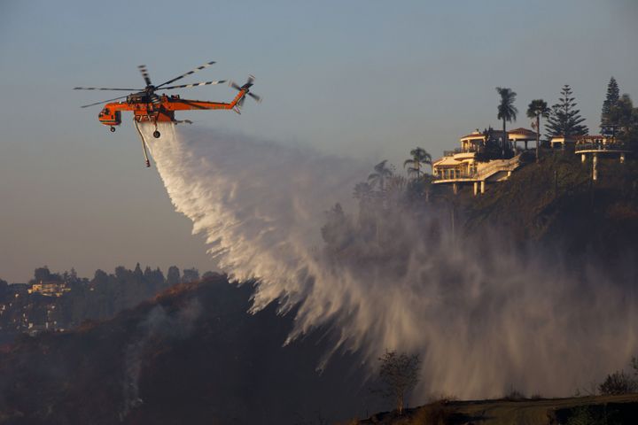 An Erickson Inc. Air Crane firefighting helicopter makes a water drop during the Skirball fire in the Bel Air neighborhood of Los Angeles on Dec. 6, 2017.