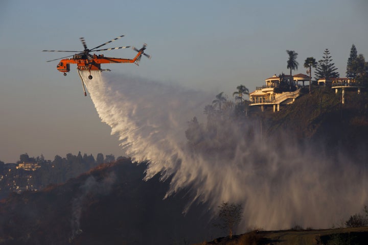 An Erickson Inc. Air Crane firefighting helicopter makes a water drop during the Skirball fire in the Bel Air neighborhood of Los Angeles on Dec. 6, 2017.