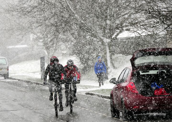 Cyclists battle through the snow falling near Castleton in the Peak District