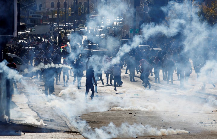 Palestinian demonstrators react to tear gas fired by Israeli troops during clashes at a protest against U.S. President Donald