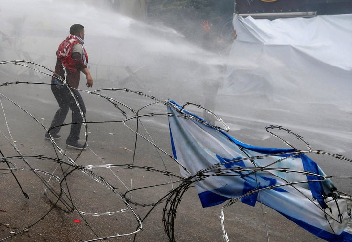 Protesters are sprayed with water near the U.S. embassy in Awkar, north of Beirut, Lebanon on December 10, 2017. (REUTERS/Mohamed Azakir)