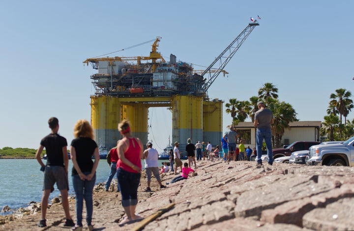 People watch tugboats transport the Hess Corp. Stampede tension leg oil platform&nbsp;on May 5. The Stampede deepwater oil an