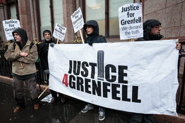 Protesters stand with a banner and placards outside Holborn Bars before a two-day hearing as part of the inquiry into the Grenfell Tower fire