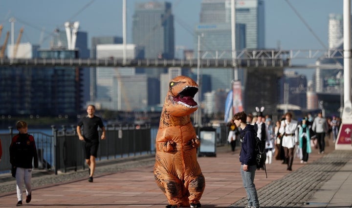 A visitor wearing a T-Rex costume arrives at the London Comic Con.