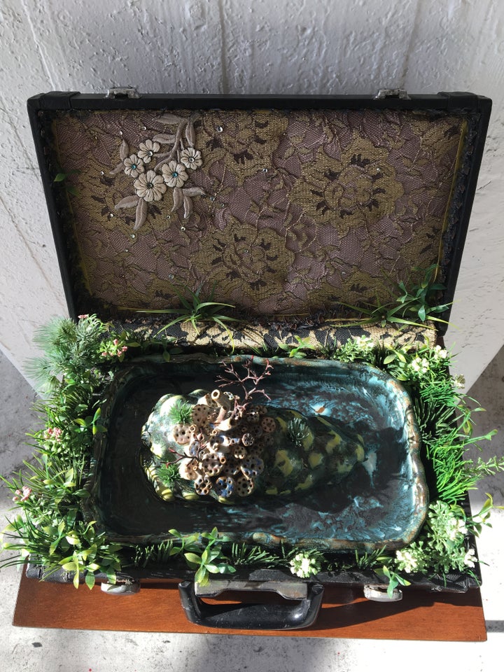<p>Lina Puerta, <em>Island of Langerhans </em>(fountain), Clay, glaze, fabric, rhinestones, applique, polyurethane foam, glue, modeling trees, paint, artificial plants, water pump, water and vintage briefcase</p>