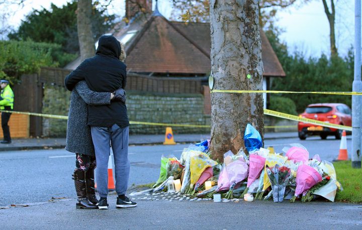 People hug at the scene of the crash after leaving floral tributes 