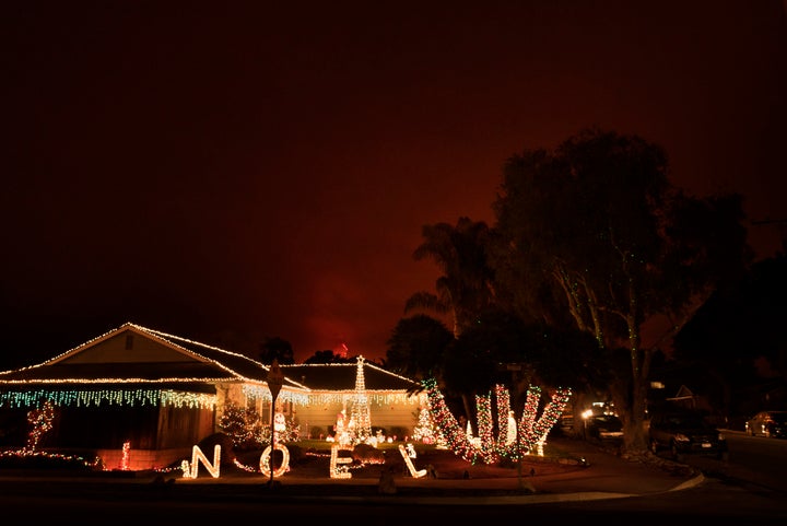 The Thomas wildfire burns behind a home decorated with Christmas lights in Carpinteria, California, on Dec. 11, 2017. Califor