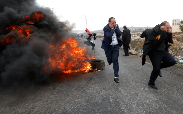 Palestinian lawyers run during clashes with Israeli troops at a protest near the Jewish settlement of Beit El, near the West