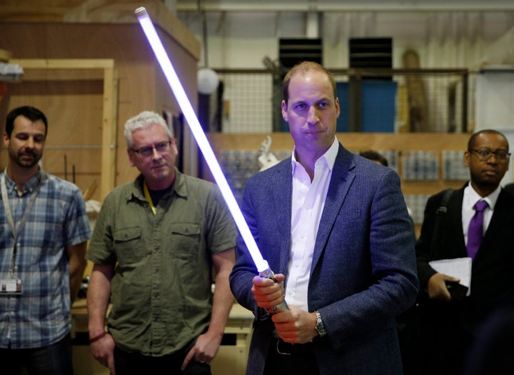 Prince William holds a lightsaber during a visit to the Star Wars film set at Pinewood Studios near Iver Heath, west of London on April 19, 2016.