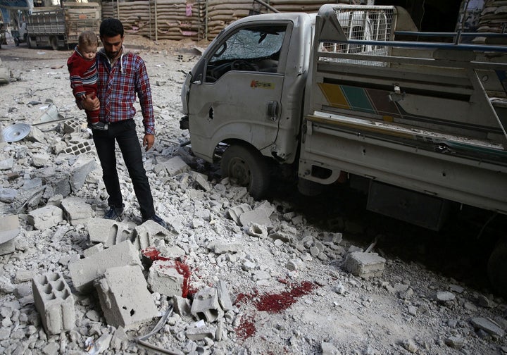 A man and child look at the rubble of damaged buildings after an airstrike on the rebel-held city of Douma on Nov. 2, 2017.