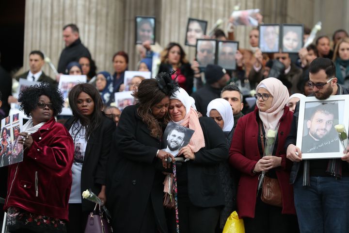 Mourners hold up pictures of lost loved ones after the Grenfell Memorial Service at St Paul's Cathedral