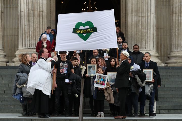 Mourners hold up photos of victims as they leave St Paul's cathedral after attending a Grenfell Tower National Memorial service