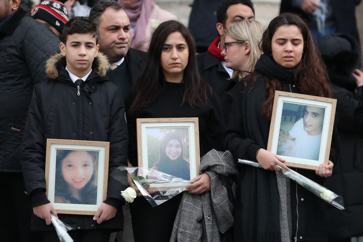 Mourners hold up photos of victims as they leave St Paul's cathedral