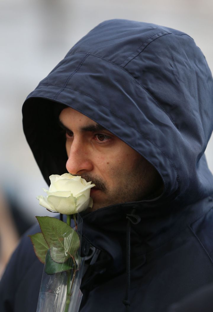  A man holds a white rose as he leaves the service 