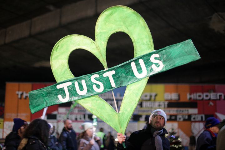 A man holds the iconic green Grenfell heart with the words 'just us' in the middle during the silent walk.